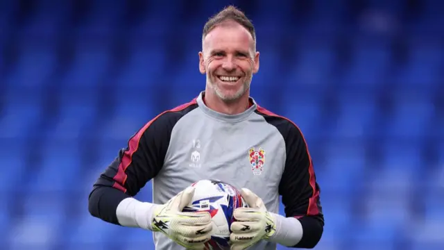 Tranmere goalkeeper Joe Murphy smiles while holding the ball