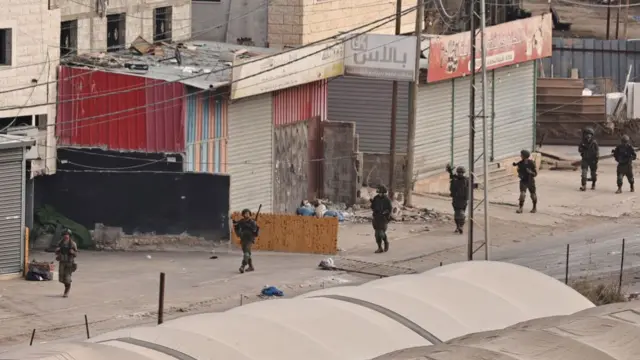 Israeli soldiers walk down a street during a raid in the al-Faraa camp for Palestinian refugees near Tubas city in the occupied West Bank