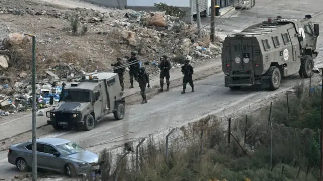 Israeli soldiers walk down a street during a raid in the al-Faraa camp for Palestinian refugees near Tubas city in the occupied West Bank