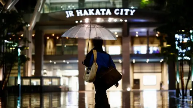 Uma mulher segura um guarda-chuva em Fukuoka, na ilha de Kyushu, no sul, na quinta-feira