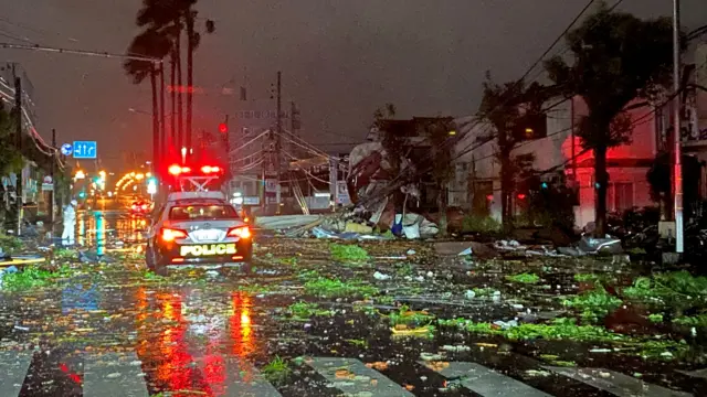 A police car drives amid the destruction in Miyazaki