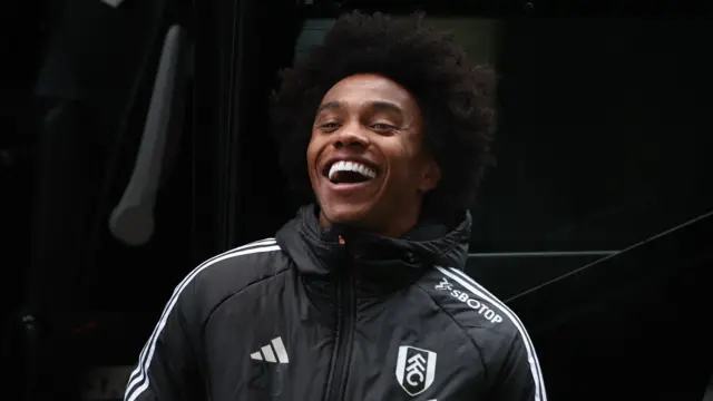 Willian laughs while wearing a Fulham tracksuit