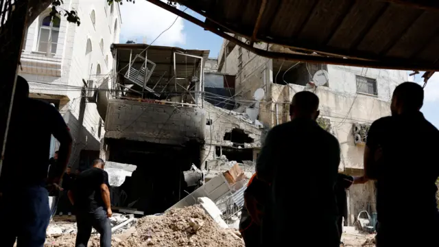 Palestinians inspect a damaged house