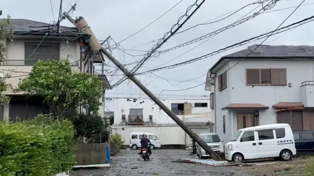 A person rides through a fallen pole following Typhoon Shanshan in Miyazaki, Japan, August 29, 2024 in this screengrab taken from a social media video