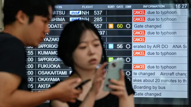 Two travellers searching for alternative flights at Haneda Airport in Tokyo