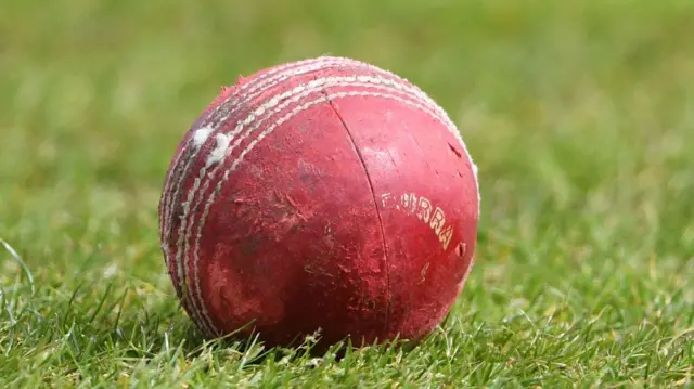 A Kookaburra cricket ball lying on a cricket pitch