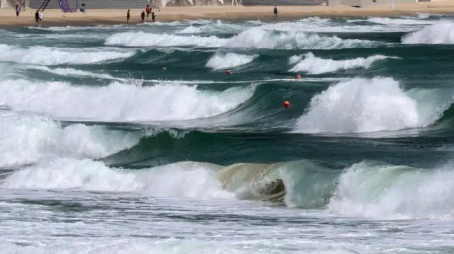 Waves crash on the shore of a beach.