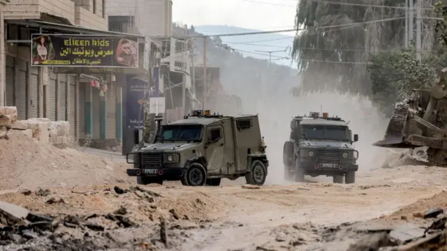 Two military vehicles drive towards the camera