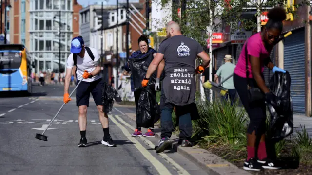 Members of the public sweep the street after violence in Sunderland