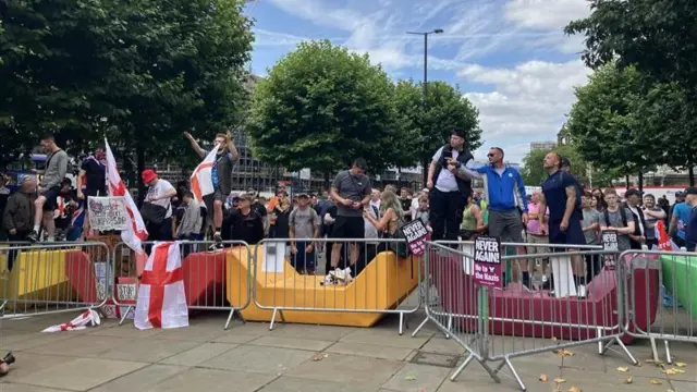 Protestors, some holding St George's flags, standing behind temporary fences