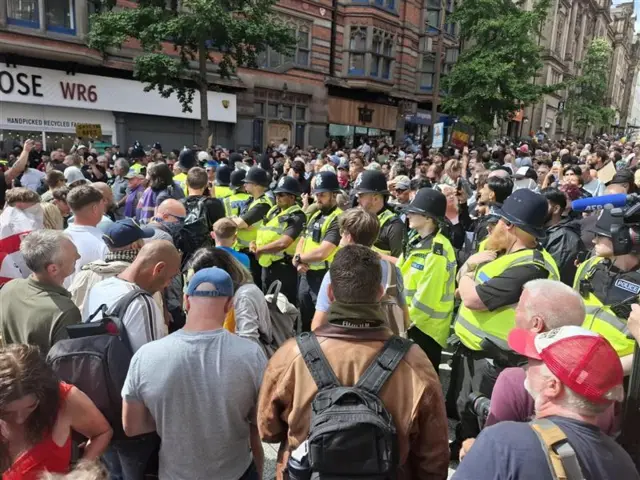 Line of police officers standing between rival protest groups