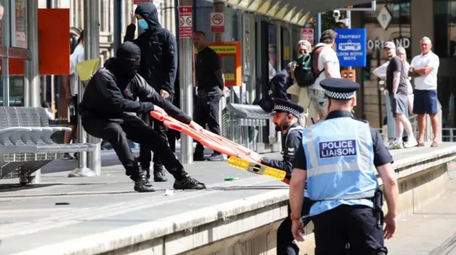 Police and protesters pulling a barrier