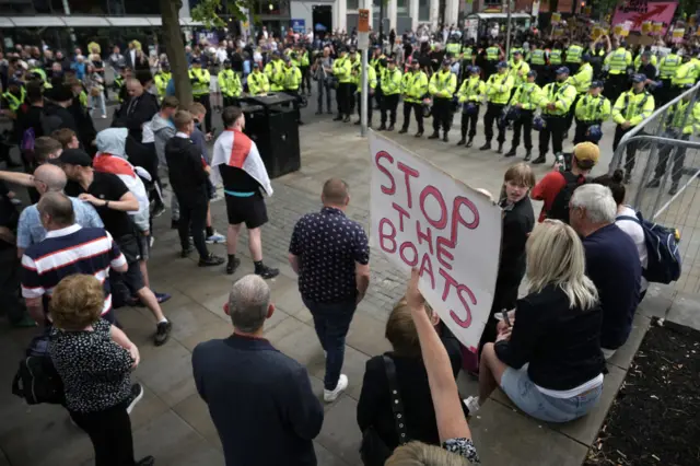 Protesters with placards "Stop the Boats" in front of a police line and an anti-racism protest