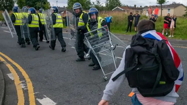 A man appears to throw a trolley at a police officer.