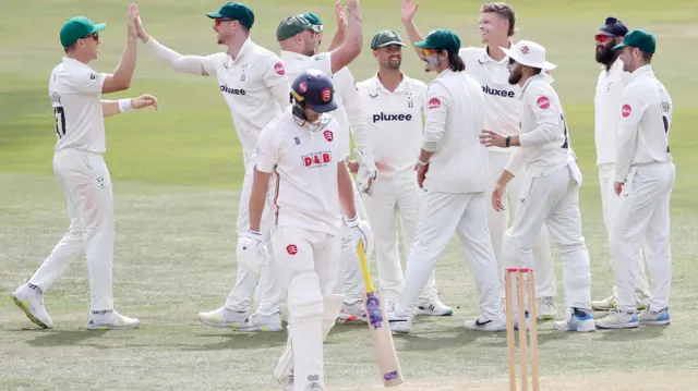 Jordan Cox walks away after being dismissed with Worcestershire players celebrating