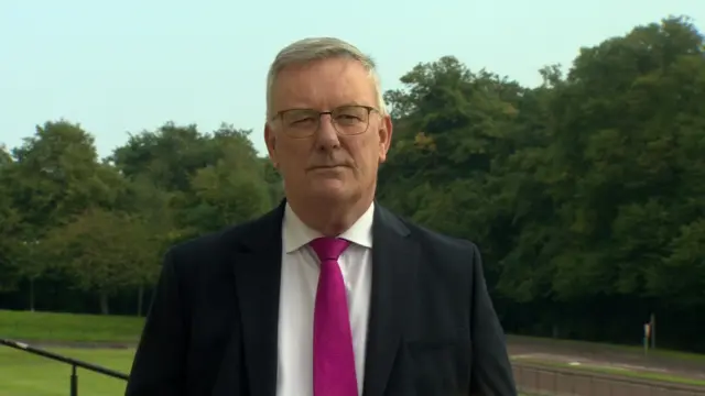 Mike Nesbitt in black suit and pink tie