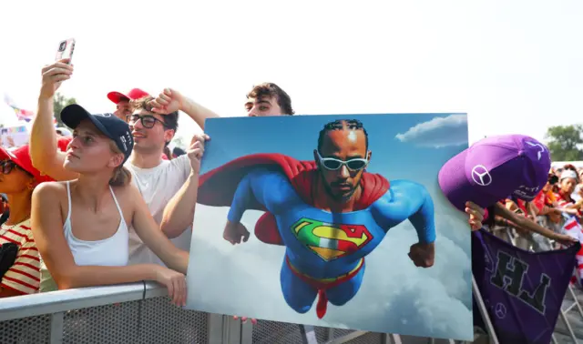 A fan holds a sign of Lewis Hamilton dressed like Superman