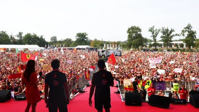 Charles Leclerc and Carlos Sainz stand in front of the tifosi