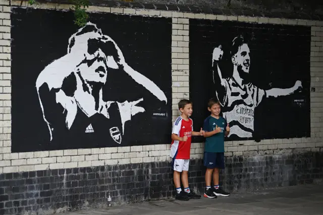 Arsenal fans pose outside a mural