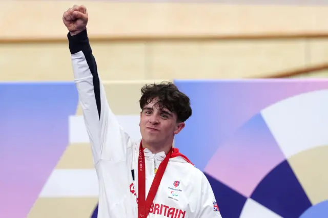 Archie Atkinson raises his fist in celebration on the podium