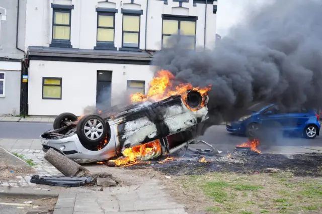 A car burns after being overturned during an anti-immigration protest in Middlesbrough. Picture date: Sunday August 4, 2024