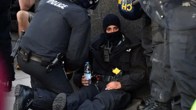 Police officers attend to a colleague during a protest in Liverpool on 3 August