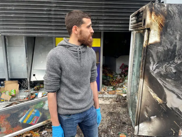 Manager Bashir outside his supermarket which was badly damaged by fire in south Belfast