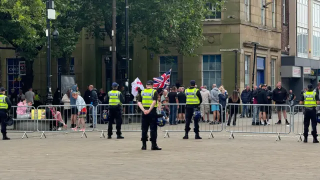 Police watch a group of protesters outside the town hall in Victoria Square, Bolton