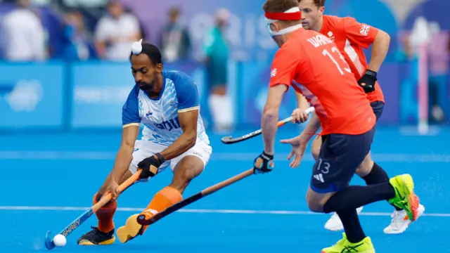 Hardik Singh of India in action with Samuel Ward of Britain.