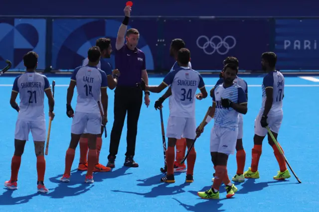 South African umpire Sean Rapaport presents a red card to India's defender #30 Amit Rohidas in the men's quarter-final field hockey match between India and Britain during the Paris 2024 Olympic Games at the Yves-du-Manoir Stadium in Colombes