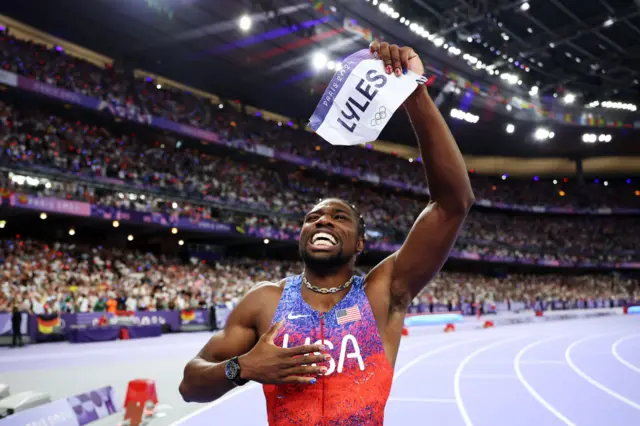 Lyles holds up hisname badge to the crowd