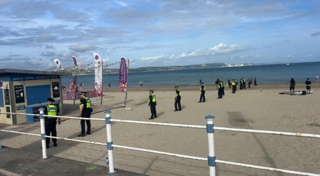 Police in a line on the beach, walking along