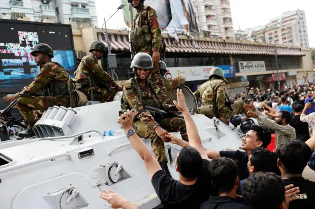 Protestors shake hands with army officers on the streets of Dhaka