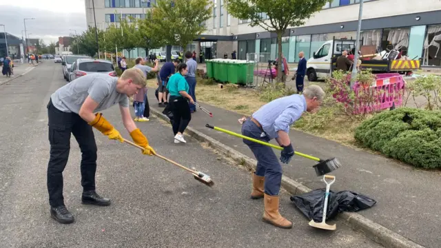 People with brooms help with cleaning up debris on the ground