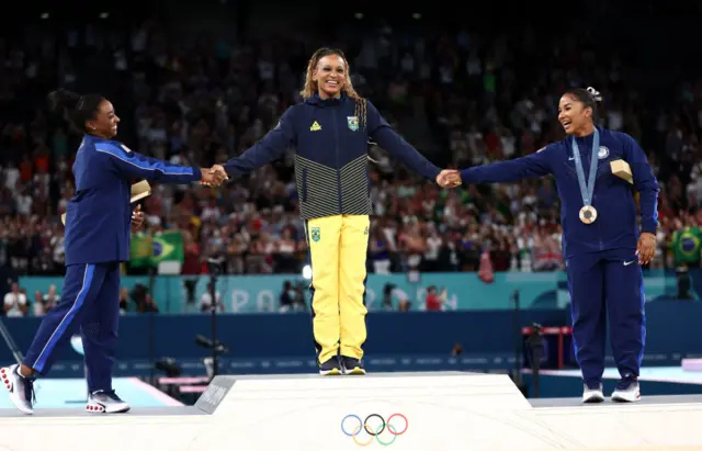 Gold medalist Rebeca Andrade (C) of Team Brazil, silver medalist Simone Biles (L) of Team United States and bronze medalist Jordan Chiles (R) of Team United States celebrate on the podium at t