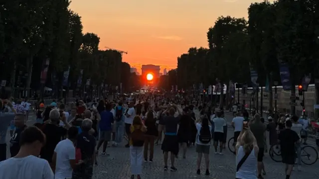 Sun sets through the Arc de Triomphe