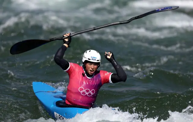 Fox celebrates her gold medal by waving her paddle in the air