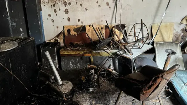 Burnt table and chairs in front of a marked wall