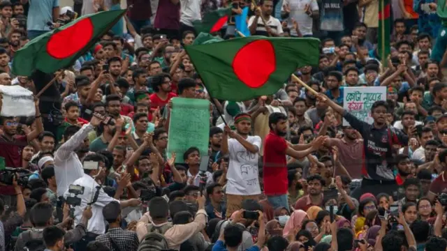 Large group of protestors in Bangladesh holding up several national flags