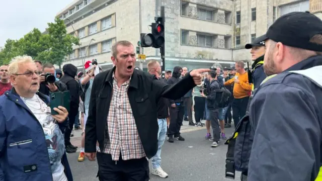 A man points his finger and shouts at a police officer