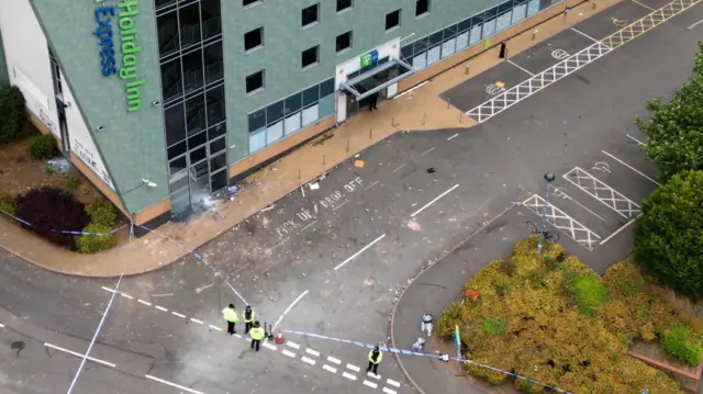 Aerial shot outside a Holiday Inn Express showing a police cordon and debris