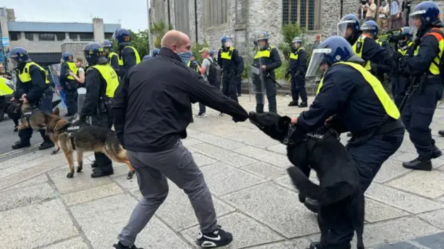 A police dog bites a man's jacket in Guildhall Square, Plymouth, last night