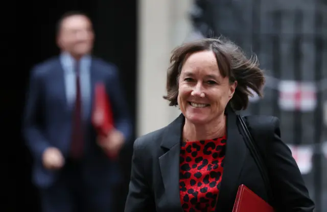 Jo Stevens in a black jacket and red blouse outside 10 Downing street with her red minster's folder