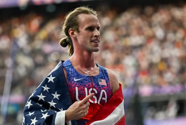 Hocker holds up his index finger to indicate number one and gold medal