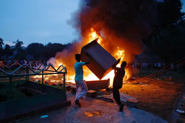 Protesters throw pieces of furniture into a fire at ex-PM Sheikh Hasina's official residence in Dhaka, Bangladesh. Photo: 5 August 2024