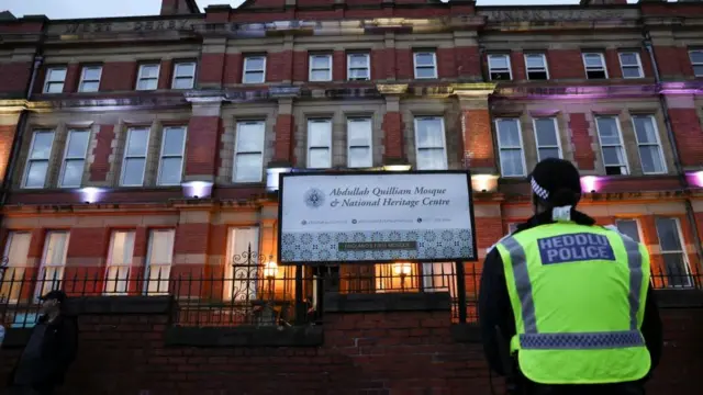 A police officer stands guards outside a mosque during a protest in Liverpool, 2 August