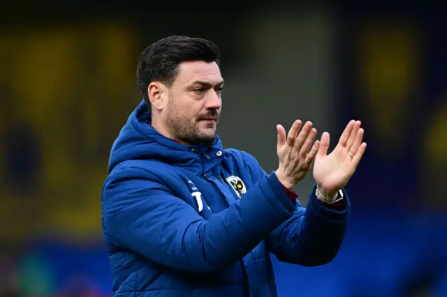 AFC Wimbledon boss Johnnie Jackson applauds the fans