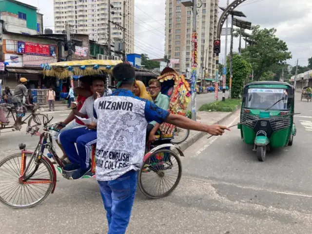 A student directs traffic in Dhaka