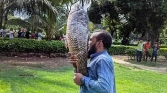 A man carrying a fish looted from Bangladesh Prime Minister Sheikh Hasina's residence.