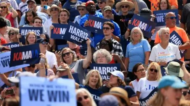 A crowd holds signs at the Harris-Walz campaign event